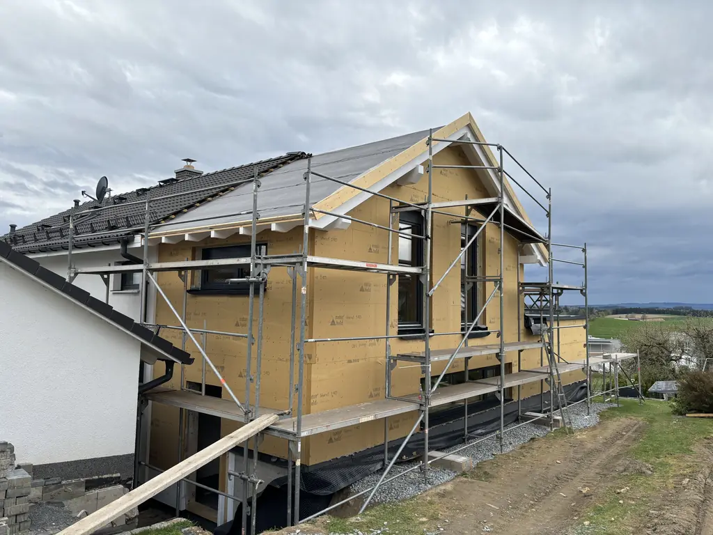Einfamilienhaus mit eingerüsteter Fassade und aufgebrachter Holzfaser-Dämmung während einer energetischen Sanierung