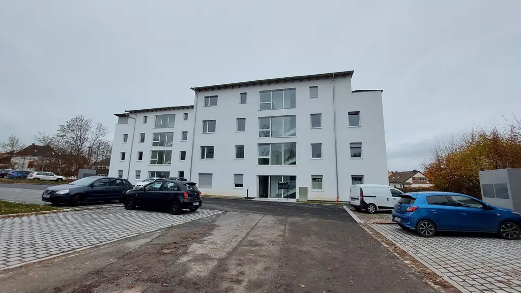 Viergeschossiges Mehrfamilienhaus mit hellem Putz kurz vor Fertigstellung