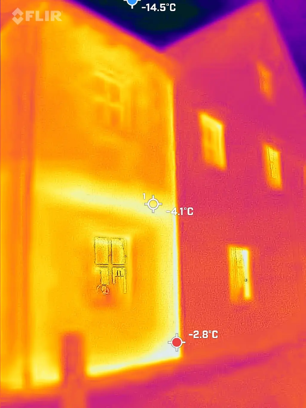 Wärmebildaufnahme einer Hausfassade mit farbig dargestellten Temperaturunterschieden